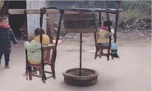 爷爷陪着孙子坐旋转木马,爸爸用铁锨做旋转木马哄孩子